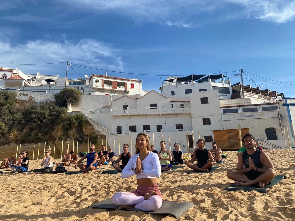 Tati Silva leading a group meditation on the beach during an international wellbeing retreat