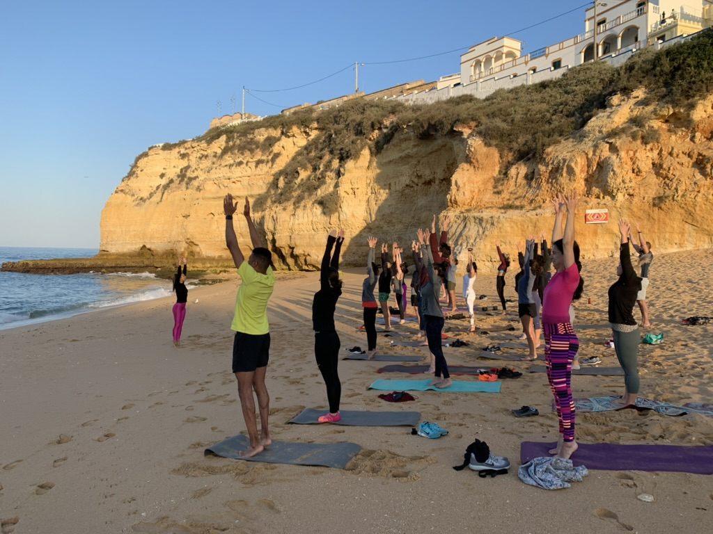 Group yoga practice on the beach during a wellbeing retreat in Portugal