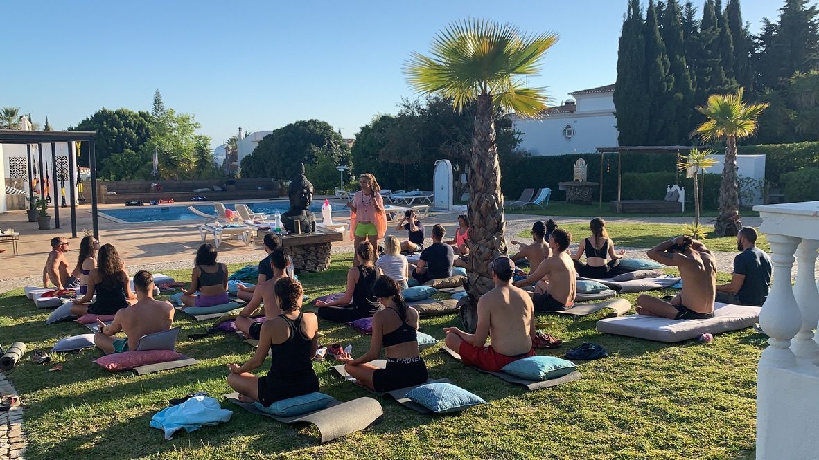 Retreat group meditating by the pool at golden hour in Portugal