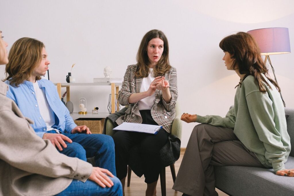 A small group of professionals sitting in a circle, with a facilitator guiding the session