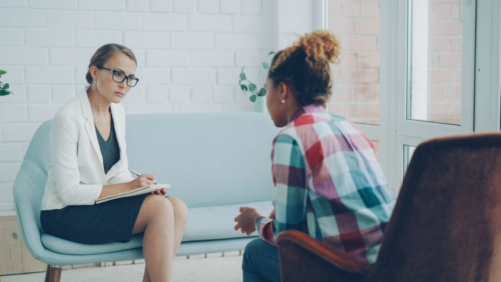 Two people talking face to face in a therapy room