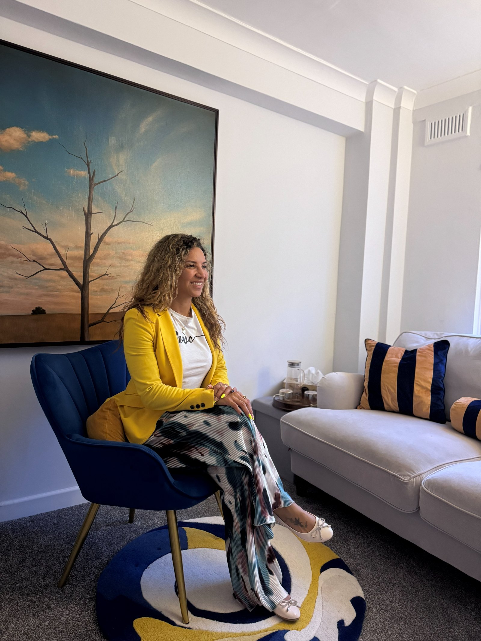Tati Silva, integrative psychotherapist, smiling in her therapy room in London